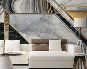 Puede incluir: Un sofá seccional blanco con almohadas marrones se encuentra frente a una pared con un patrón geométrico de mármol negro, blanco y dorado. La pared presenta un diseño abstracto moderno con acentos dorados.