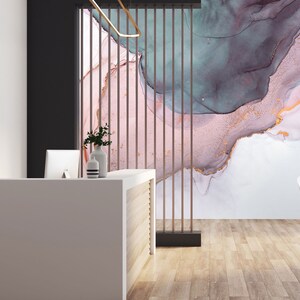 May include: A modern office reception area with a white desk and a chair. The wall behind the desk features a large abstract painting with pink, blue, and gold colours.