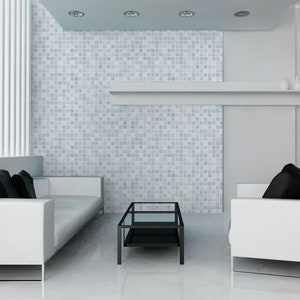 May include: A white living room with two white sofas, black pillows, and a black glass coffee table. The wall behind the sofas is covered in blue and white mosaic tiles.