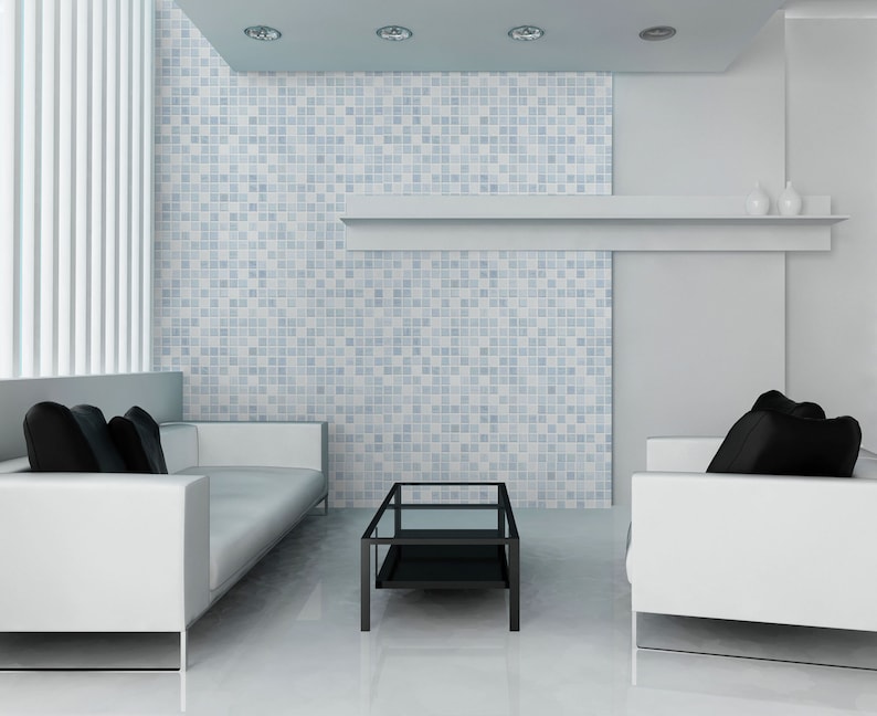 May include: A white living room with two white sofas, black pillows, and a black glass coffee table. The wall behind the sofas is covered in blue and white mosaic tiles.