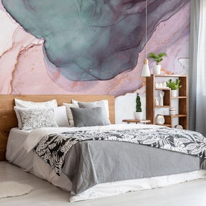 May include: A bedroom with a grey and white patterned bedspread, a wooden headboard, and a pink and blue abstract wall mural. There are two bedside tables with plants and lamps.