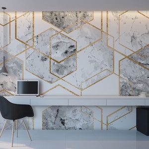 May include: A white desk with a black chair and a laptop computer. The wall behind the desk has a geometric pattern of gold lines on a white marble background.