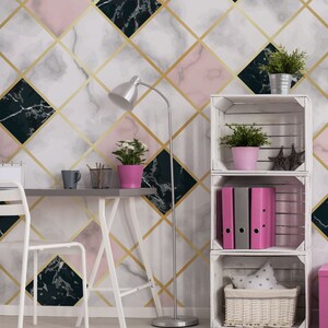 May include: A modern interior with a geometric marble wallpaper design in pink, white, and black, accented with gold lines. A desk, chair, and shelving unit are visible, along with potted plants and office supplies. The room is well-lit with a silver floor lamp.