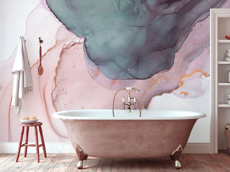 May include: A freestanding bath with a gold tap in a bathroom with a pink, white and teal abstract watercolour wallpaper.