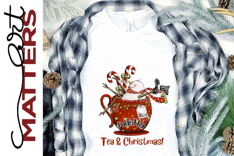 K&ouml;nnte beinhalten: Ein wei&szlig;es T-Shirt mit einem roten Becher-Design, das einen Schneemann, Zuckerstangen und den Text "Fueled by Tea & Christmas!" zeigt.