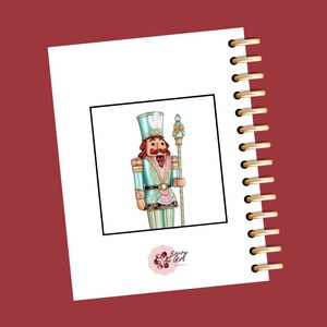 May include: A teal and gold nutcracker figurine with a red mustache and a white feather on his hat. The nutcracker is holding a gold and white staff. The image is framed in black and has a pink flower logo with the text "Every Girl Planner" at the bottom.