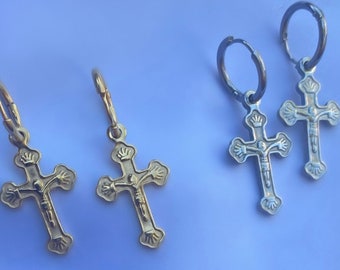 Puede incluir: Tres pares de pendientes de cruz de oro y plata. Las cruces están detalladas con una figura de Jesucristo. Los pendientes están sobre un fondo blanco.