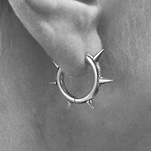 May include: Silver hoop earrings with sharp spikes around the edge.