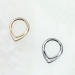 May include: Two simple rings with a teardrop shape. One ring is gold and the other is silver.