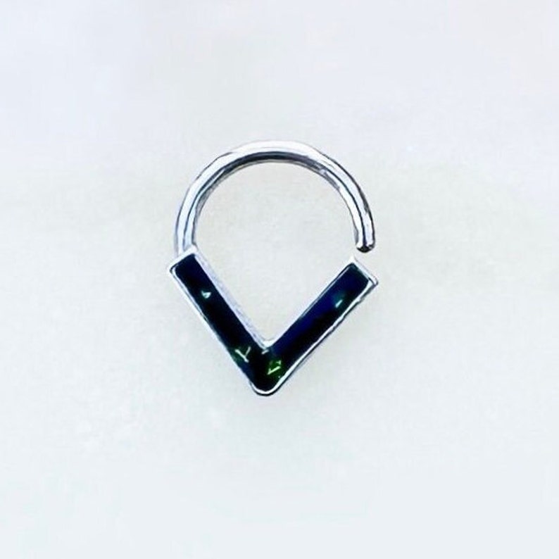 May include: A silver hoop earring with a black and green V-shaped design.