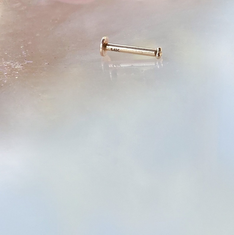 May include: A gold 14k nose stud with a small round gem on the end.