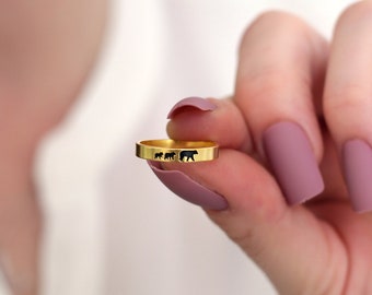 Könnte beinhalten: Ein goldener Ring mit einer Silhouette einer Bärenfamilie, die in einer Reihe geht.