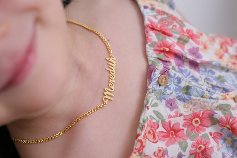 Pu&ograve; includere: Una collana a catena d'oro con il nome "Meredith" scritto in corsivo.