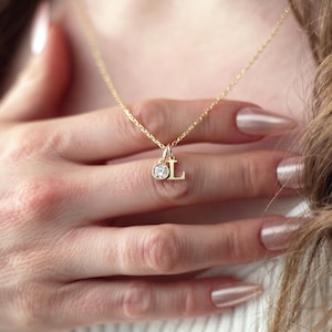 May include: A gold necklace with a small diamond and the letter L pendant.