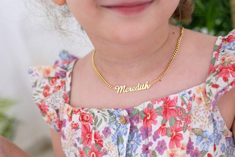 Pu&ograve; includere: Una collana a catena dorata con una targhetta con il nome in corsivo che recita "Meredith".