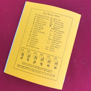 May include: A yellow page from a book with a list of proofreader's marks and their corresponding symbols. The page also includes a diagram showing the difference between letters that look similar, such as 'p' and 'b', 'q' and 'd', and 'u' and 'n'.