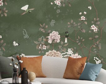 May include: A living room interior with a white curved sofa, two blue armchairs, and a coffee table. The wall is covered in a green wallpaper with a floral pattern and birds. The room is decorated with plants and pillows.