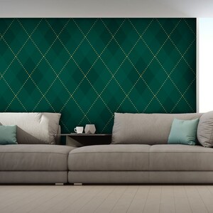 Op de afbeelding: Een grote, grijze hoekbank met twee tealblauwe kussens staat voor een muur met een groene en gouden diamantpatroon behang.