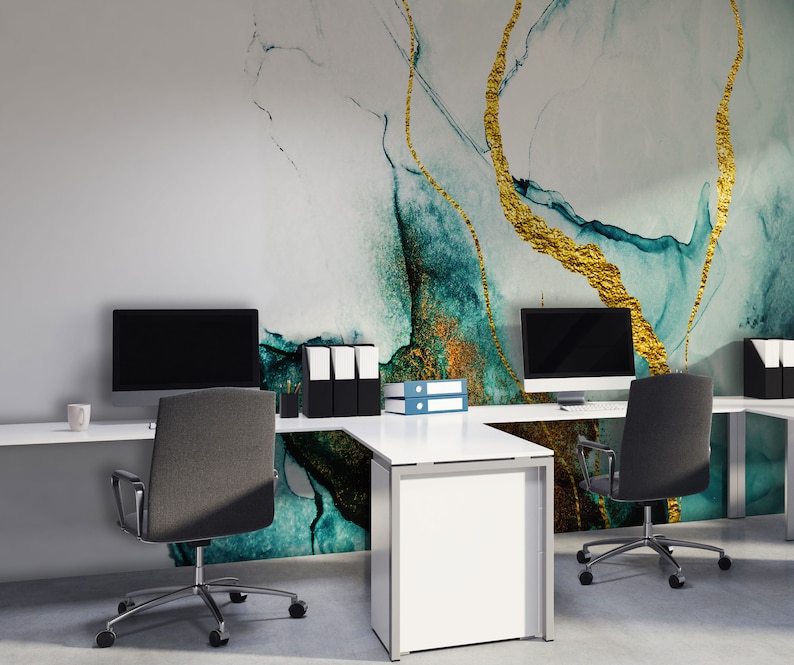 Peut inclure: Un espace de travail moderne avec deux bureaux blancs et des chaises de bureau noires. Le mur derri&egrave;re les bureaux pr&eacute;sente un papier peint abstrait bleu sarcelle et or.