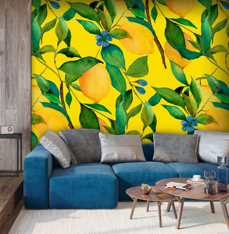 Puede incluir: Un sof&aacute; azul con almohadas frente a una pared amarilla con un patr&oacute;n de acuarela de limones y hojas verdes.