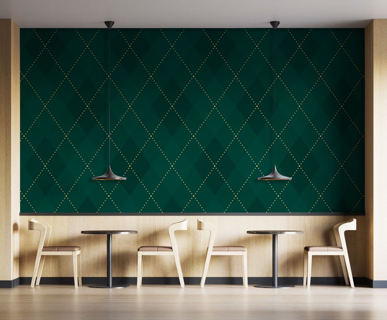 Op de afbeelding: Een groene en gouden gepatroneerde muur met drie zwarte hanglampen die boven een rij van drie houten stoelen en tafels hangen. De stoelen en tafels zijn symmetrisch gerangschikt.
