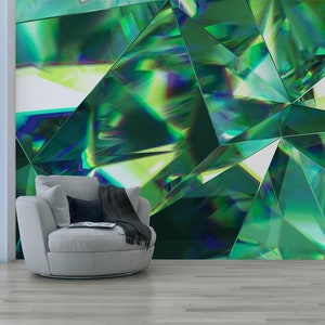 May include: A gray armchair with a black throw blanket sits in front of a wall with a green, geometric, abstract pattern.