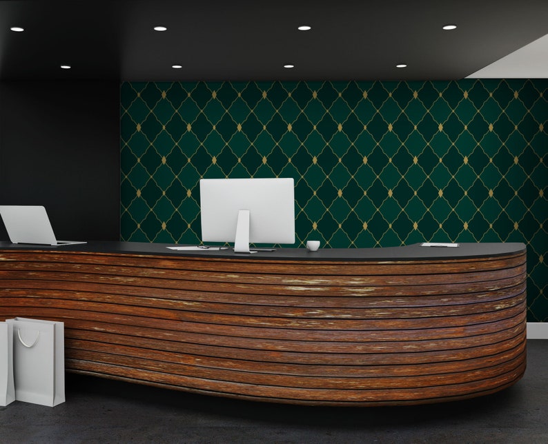 May include: A wooden reception desk with a curved front and a dark wood finish. The desk has a black countertop and two computers on it. The wall behind the desk is covered in a green and gold wallpaper with a geometric pattern.