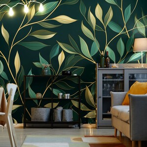 May include: A room with a dark green and gold leaf wallpaper. The wallpaper features large, stylized leaves in shades of green and gold. The room is furnished with a gray sofa, a gray cabinet, and a black metal shelf. A string of lights hangs from the ceiling.
