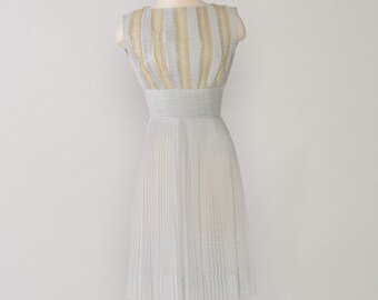 May include: A light blue sleeveless dress with a pleated skirt and a gold and white striped bodice.
