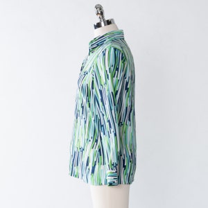 May include: A long-sleeved shirt with a blue, green, and white abstract pattern. The shirt has a button-down collar and a long sleeve.