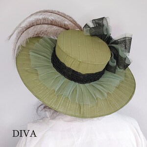 May include: A wide-brimmed olive green hat with a black band and a large bow. The hat features a layered design with tulle and feathers. The word "DIVA" is printed at the bottom of the image.