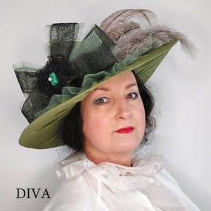 May include: Olive green hat with black lace and tulle accents, adorned with a black flower and a turquoise gem. The hat features gray feathers and the word "DIVA" in black text.