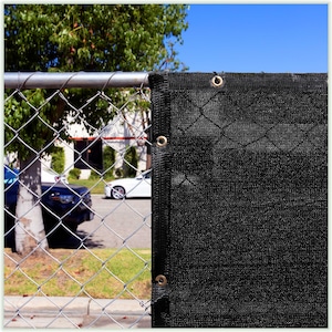 May include: Black construction fence privacy screen with metal grommets. The screen is made of a mesh material and is attached to a chain link fence.
