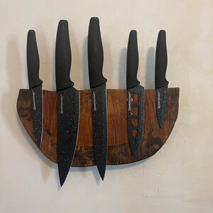 May include: A wooden knife holder with six black knives with the word "GraniteStone" printed on each knife.