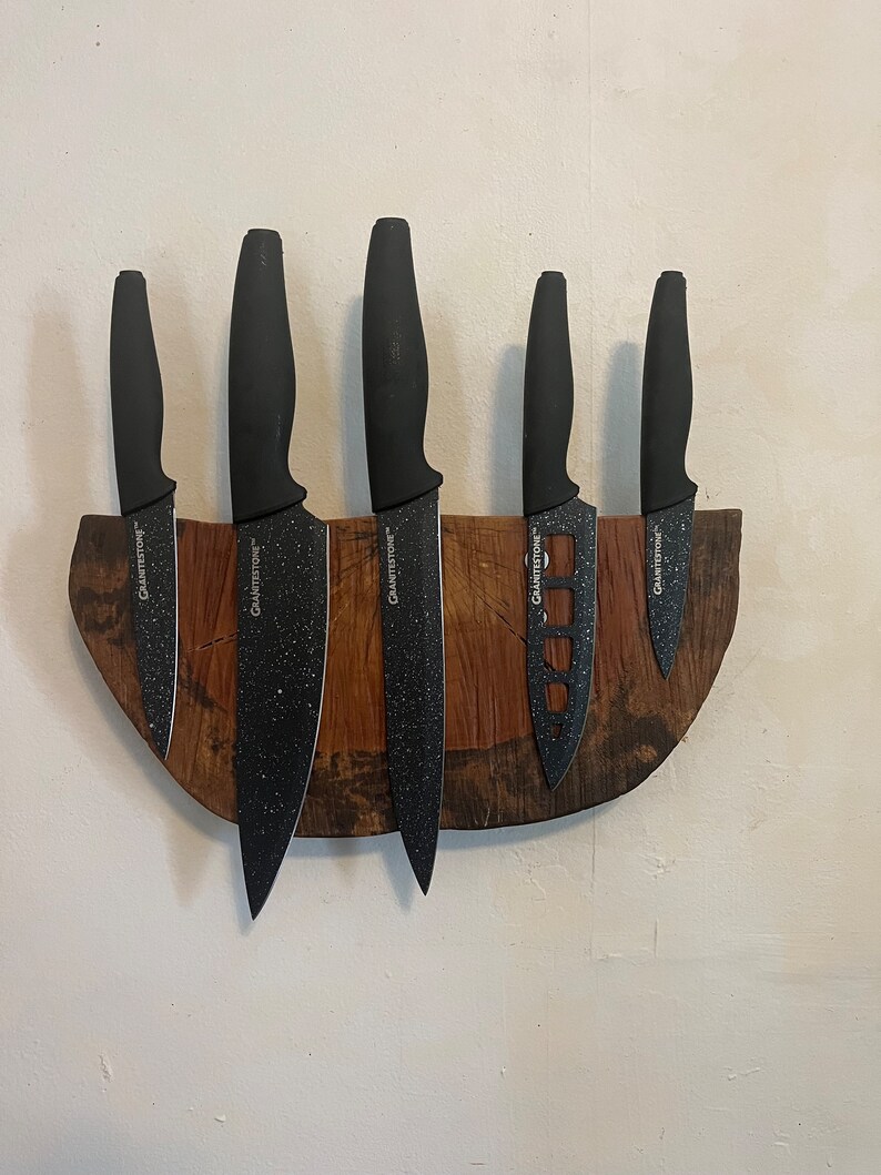 May include: A wooden knife holder with six black knives with the word "GraniteStone" printed on each knife.