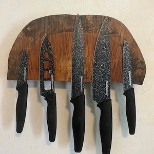 May include: A set of six black kitchen knives with black handles and a speckled finish. The knives are mounted on a wooden magnetic strip.