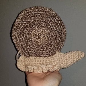 Puede incluir: Un caracol de ganchillo con una concha marrón y beige y un cuerpo beige.