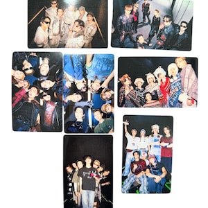 May include: A collection of seven rectangular photo cards featuring various group portraits of a musical ensemble. The images display members in diverse outfits, including casual wear, patterned sweaters, and dark jackets, captured in indoor and outdoor settings with varied lighting and poses.
