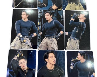May include: A collection of nine rectangular photo cards featuring a person with dark hair wearing a black long-sleeved shirt, a silver chain necklace, and light-colored pants. The person is shown in various poses, often holding a microphone and wearing black gloves while performing on a stage.