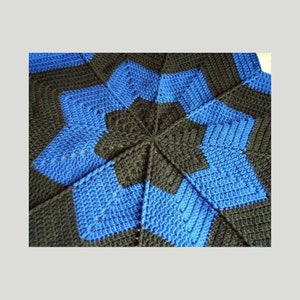Może przedstawiać: Koc wykonany na szydełku z wzorem gwiazdy w odcieniach niebieskiego i czarnego.