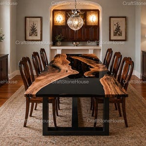 May include: A large, rectangular dining table with a black epoxy resin center and natural wood edges. The table is supported by a black metal base and surrounded by wooden chairs. The room has a neutral color palette.