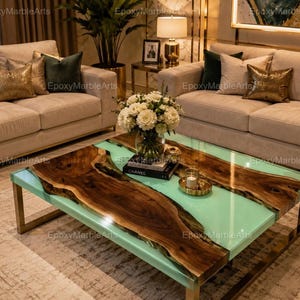 May include: A rectangular coffee table featuring a live edge wood slab centerpiece integrated with a smooth, light mint green epoxy resin surface. The table is supported by a metallic gold frame and base, showcasing a natural wood grain pattern.