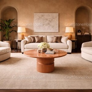 May include: A stylish living room with a beige sofa, armchairs, and a round coffee table. The room is decorated in neutral tones, with a large rug, lamps, and a plant. The text "CraftStoneHouse" is visible.