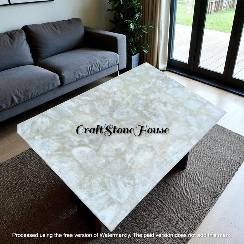 May include: A rectangular coffee table with a light-colored, patterned stone top. The table has a dark base and sits on a neutral-colored rug. The text "Craft Stone House" is visible on the table's surface.