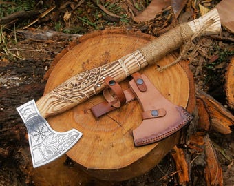 May include: A hand-crafted axe with a wooden handle and a leather sheath. The handle is decorated with intricate carvings and the axe head features a detailed design.