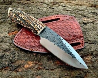 Coltello da caccia artigianale in acciaio al carbonio con manico in corno di cervo e fodero in pelle.