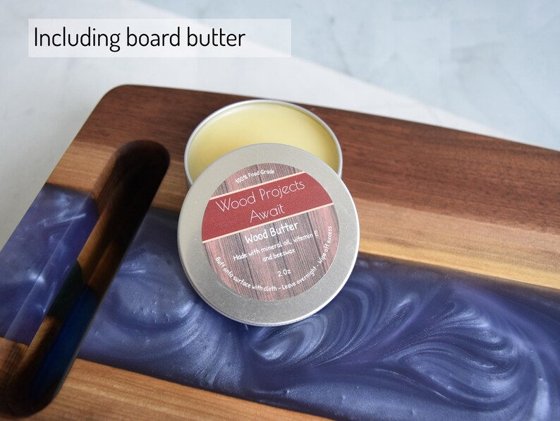 Op de afbeelding: Een klein blikje houtboter, met het label "Wood Projects Await", met de tekst "100% Food Grade" en "Made with mineral oil, vitamin E and beeswax". Het blikje staat op een houten snijplank met een blauwe harsinleg.