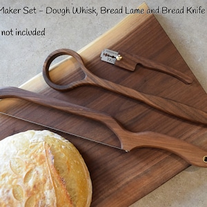 May include: A set of three wooden bread making tools on a wooden chopping board. The tools include a dough whisk, a bread lame, and a bread knife. A loaf of bread is also on the board. The text "Bread Maker Set - Dough Whisk, Bread Lame and Bread Knife" and "*Board not included" is visible in the image.