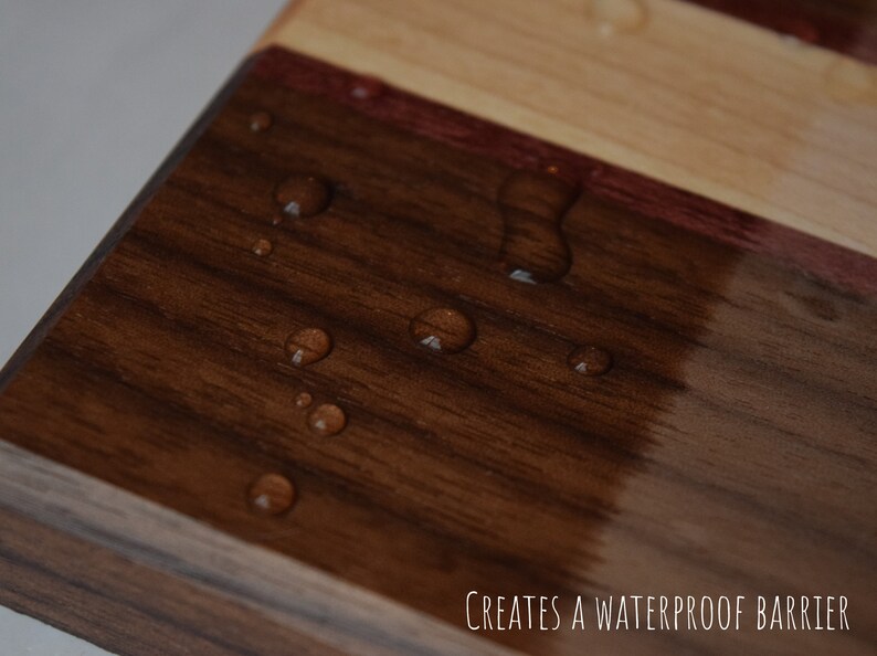 May include: Close-up of a wooden chopping board with a dark brown finish. Water droplets bead on the surface, demonstrating the waterproof barrier created by the finish.