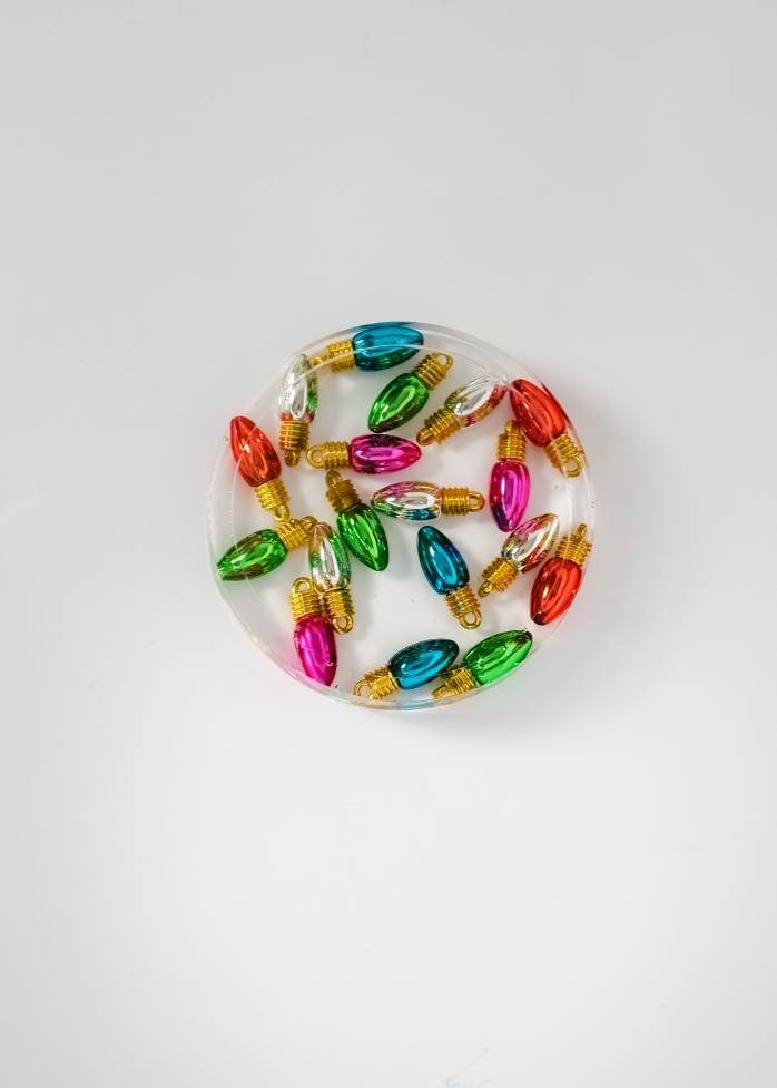 Clear epoxy resin coaster with Christmas light charms. Made To Etsy